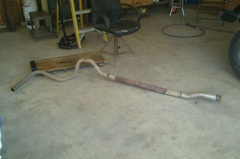 1987 Ford Bronco - A used exhaust pipe lies on a concrete floor, indicating wear and a repair.