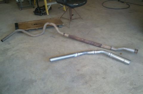 1987 Ford Bronco - Two exhaust pipes are laid out on a concrete floor, possibly for replacement or repair.