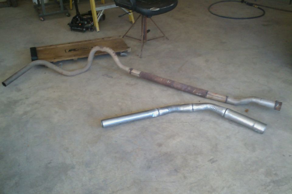 Two exhaust pipes on a concrete floor, one appears rusted
