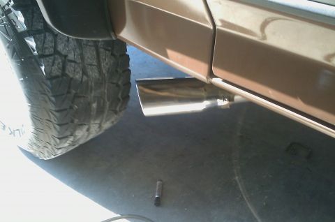 1987 Ford Bronco - Close-up of a vehicle's side panel, showing a chrome exhaust pipe and a tire.