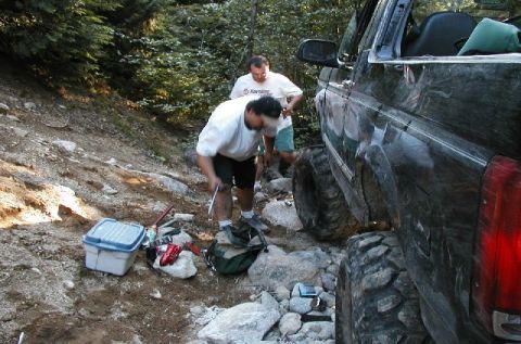 1993 Ford Bronco - A dark green Ford Bronco is seen on a rocky trail with two men attending to it.