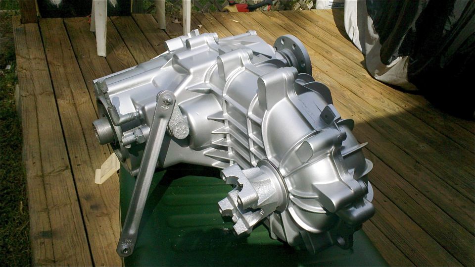 silver transfer case sitting on a green surface on a wooden deck