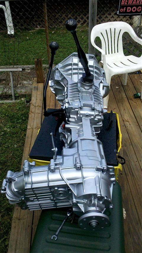 1995 Ford F-150 - A silver ZF5 transmission and transfer case assembly with two black shifters is displayed outdoors on a wooden surface.