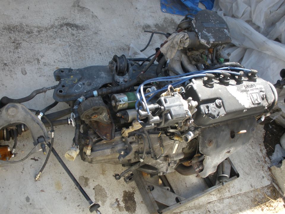 Honda engine assembly with wiring and exhaust manifold. Some parts are covered in dust