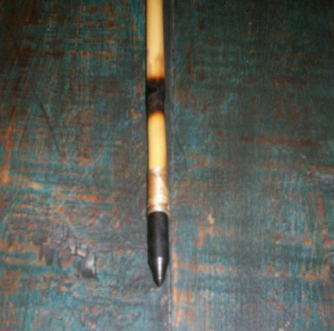 1993 Ford Bronco - A close-up view of a part with a black tip and tan shaft, wrapped with tape, resting on a textured teal surface.