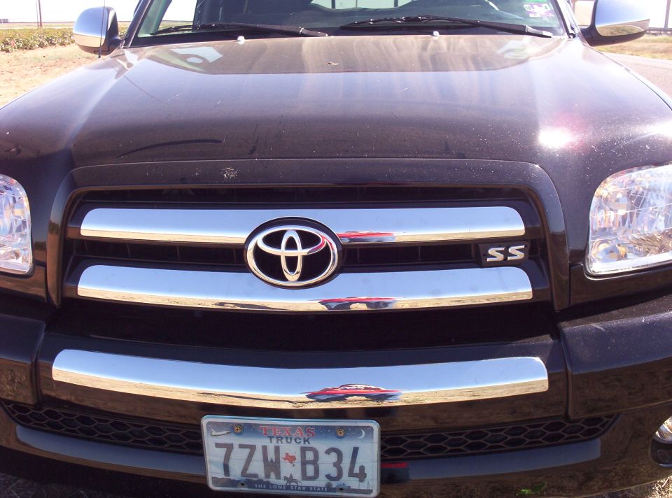 Front grille and headlights of a dark-colored Toyota Tundra with a Texas license plate