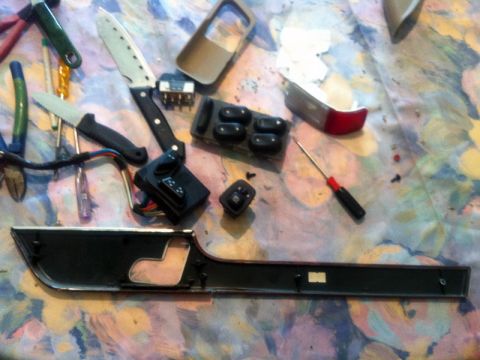 2001 Mercury Grand Marquis - Disassembled car door interior trim and electronic controls are laid out on a patterned surface.