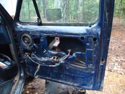 1985 Ford Bronco - Interior view of a blue vehicle door, showing the speaker and wiring harness with the door panel removed.