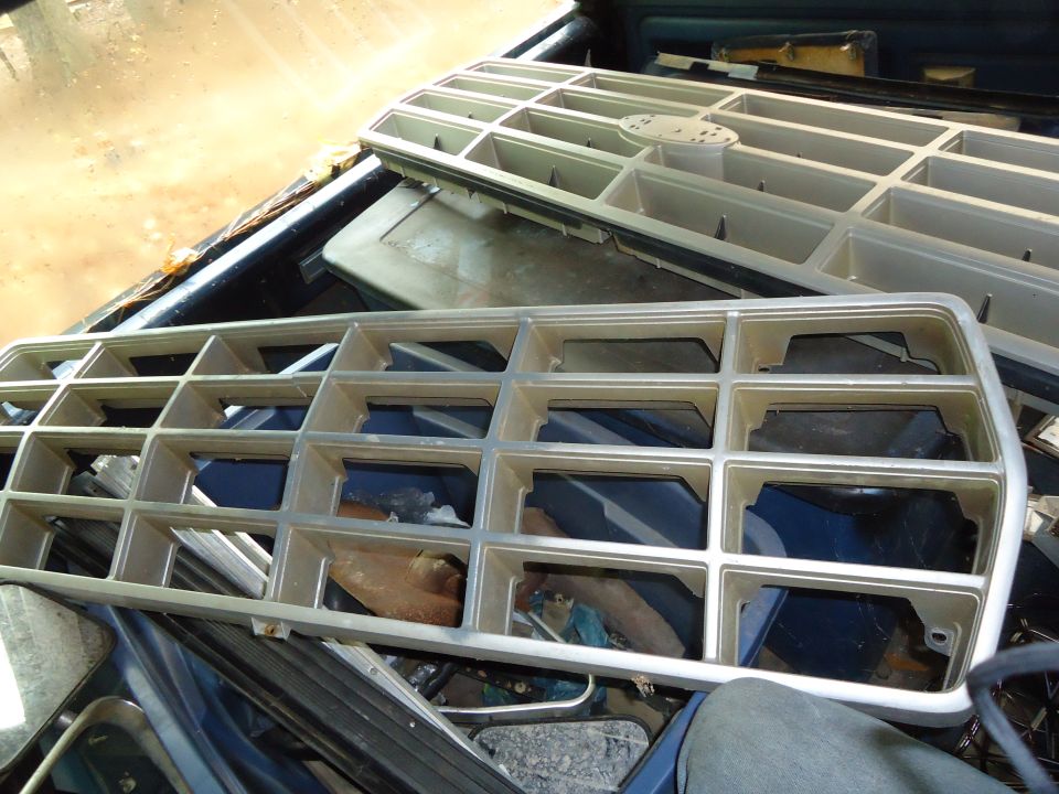 Two vehicle grilles are stacked in the bed of a truck