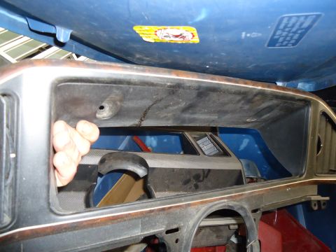 1985 Ford Bronco - A close-up view of a vehicle's dashboard cavity, revealing internal components and a hand interacting with the space.
