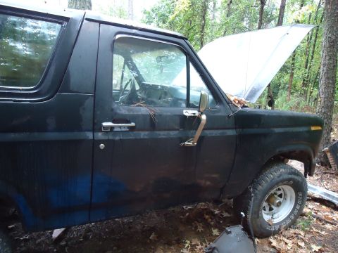 1985 Ford Bronco - Side view of a black SUV with its hood open, showing a body style consistent with the early 1980s.