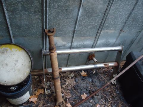 1985 Ford Bronco - A rusty driveshaft and a chrome bull bar are visible next to a metal wall and some buckets.