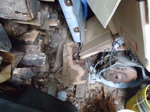 1985 Ford Bronco - Transmission and various car parts are stored amongst wood and cardboard boxes.
