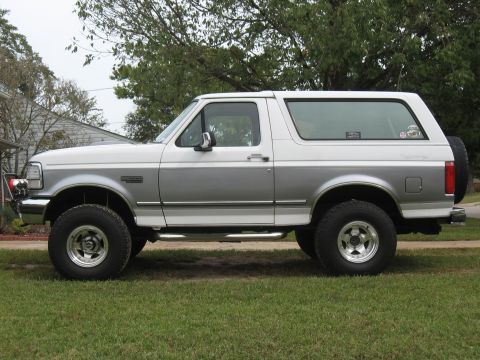 1994 Ford Bronco - This two-tone 1994 Ford Bronco is shown from the side, parked on a grassy lawn.