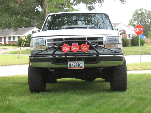 1994 Ford Bronco - A white 1992 Ford Bronco is parked on a grassy lawn, facing the camera with a bull bar and auxiliary lights.