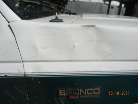 1996 Ford Bronco - Close-up of a dented and scratched 1996 Ford Bronco fender and hood.