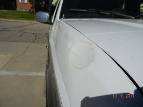 1996 Ford Bronco - A white SUV's fender shows damage, with a circular stain and scuff marks visible.