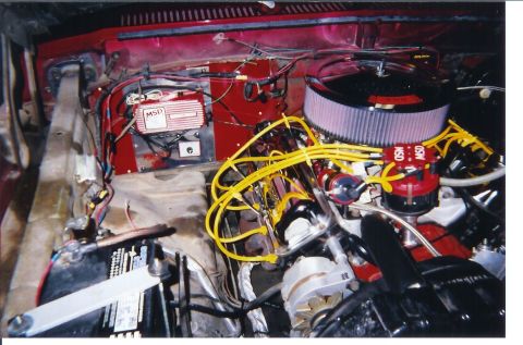 1978 Ford Bronco - Engine bay of a red truck with a red-painted V8 topped by a large round K&N-style air filter, yellow MSD plug wires and an MSD ignition box…