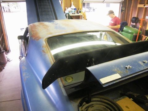 1970 Ford Mustang - A blue muscle car is parked in a garage with its hood and trunk open, revealing its current state of disrepair.