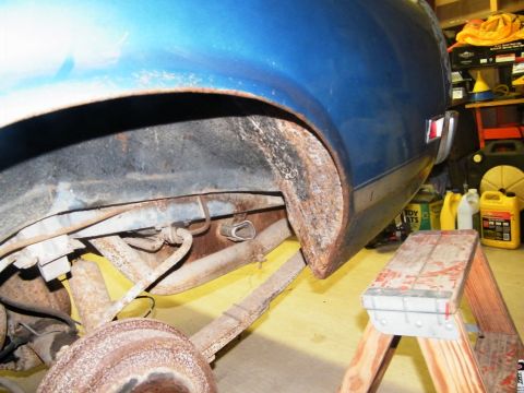 1970 Ford Mustang - Close-up of the rear wheel well and suspension on a 1970 Ford Mustang, showing signs of rust.