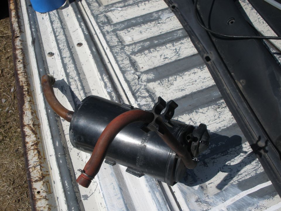 Exhaust muffler with red hose attached, sitting on a truck bed