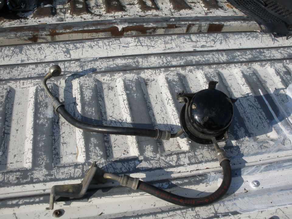 Automotive part with hoses and a black canister, lying on a truck bed