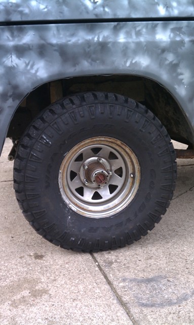 1978 Ford Bronco - Close-up of a vehicle's side wheel and fender, showing a gray primer paint job and an off-road tire.
