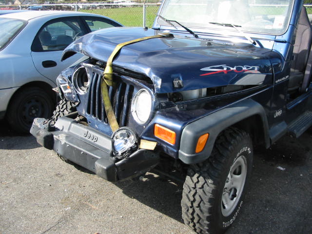 Dark blue Jeep Wrangler with front-end crash damage and yellow tow strap