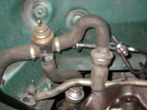 1990 Ford Bronco - Close-up view of engine hoses and a brass valve assembly, likely part of the emissions system.