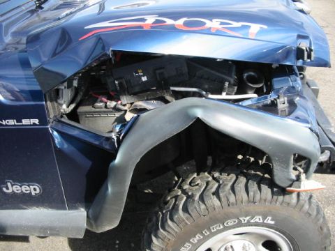 2002 Jeep Wrangler - This 2002 Jeep Wrangler shows significant front-end damage, including a crumpled hood and fender, revealing internal components.