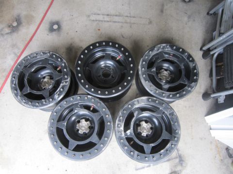 1996 Ford Bronco - Five black aftermarket wheels with beadlock rings are laid out on a concrete surface.