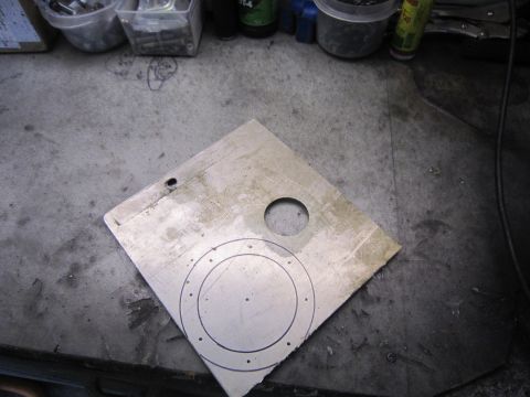 1974 Ford Bronco - A metal plate with markings and holes is shown on a workbench.