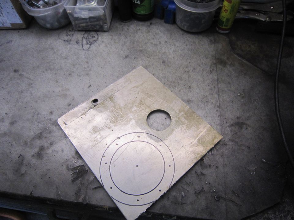 Metal plate with two concentric circles and dots marked on it, plus a circular hole and a smaller hole