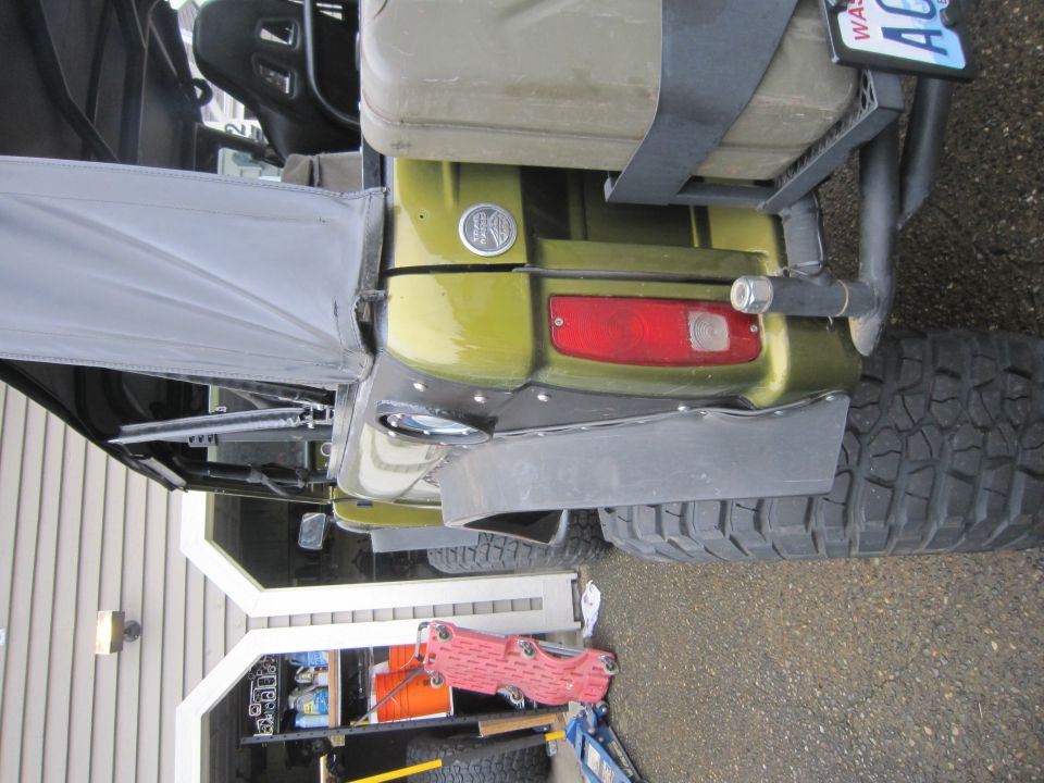 Rear view of a green off-road vehicle with a jerrycan mounted on the back. A Washington license plate is visible