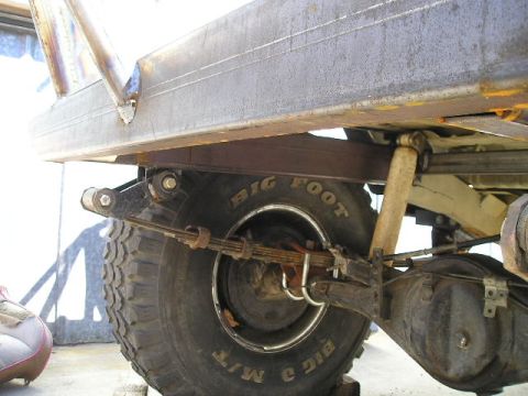 1987 Suzuki Samurai - Close-up view of the rear suspension and tire of a vehicle, showing leaf springs and a shock absorber.