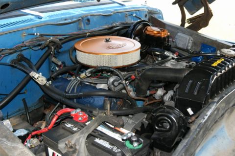 1978 Ford Bronco - The engine bay of a blue 1978 Ford Bronco, showing the air filter, radiator, and battery.