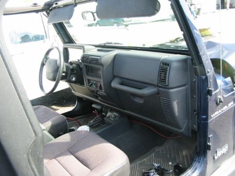 2002 Jeep Wrangler - The interior of a 2002 Jeep Wrangler, its dashboard, steering wheel, and seats, is visible in this photograph.