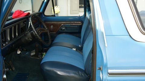 1978 Ford Bronco - Interior of a 1978 Ford Bronco with blue vinyl and cloth seats and a red hat on the dash.