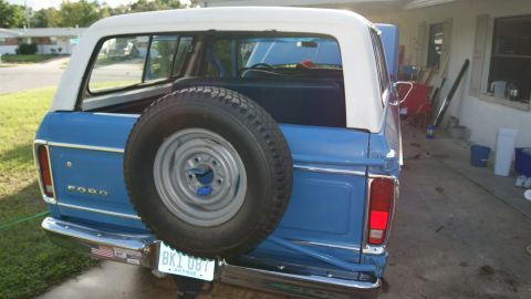1978 Ford Bronco - Rear view of a blue 1978 Ford Bronco with a white hardtop and a spare tire on the tailgate.