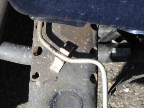 2002 Jeep Wrangler - A close-up view of a vehicle's undercarriage, focusing on the frame and a brake line. The watermark indicates the source.
