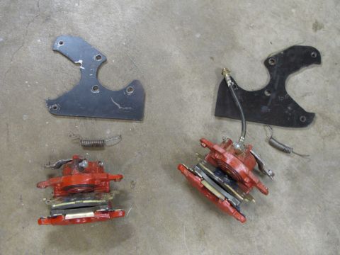 1995 Ford Bronco - Disassembled brake calipers and mounting hardware laid out on a concrete surface.