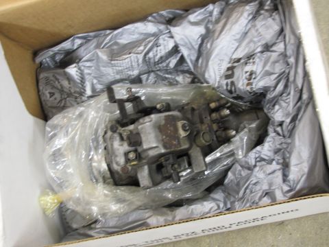 1995 Ford Bronco - A fuel injection pump is shown inside a cardboard box, protected by plastic wrap and crumpled packing paper.
