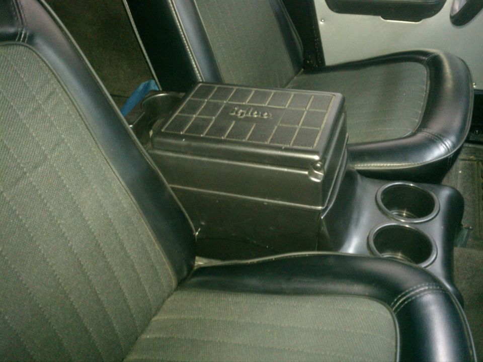 Black vehicle center console armrest between two cloth-and-vinyl seats