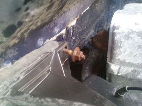 1994 Ford Bronco - A close-up view of a rusty bolt and bracket within the engine bay, with various hoses and components partially visible.