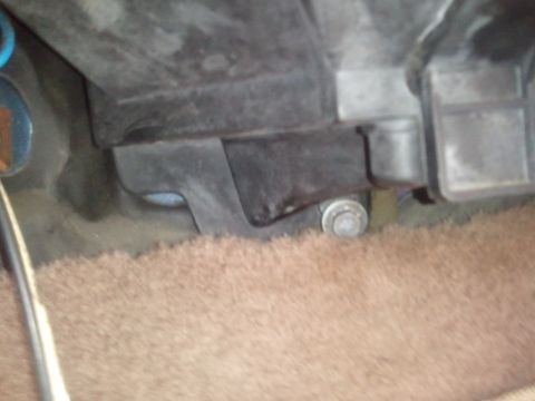 1994 Ford Bronco - Close-up view of an AC system component mounted above a carpeted floor, showing a bolt securing the part.