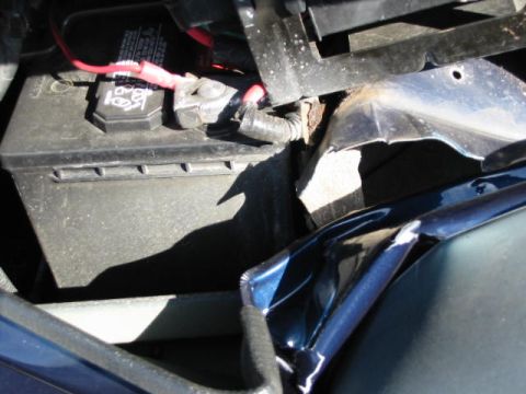 2002 Jeep Wrangler - Close-up view of a car battery and damaged engine bay components.