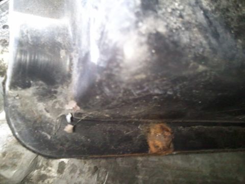 1994 Ford Bronco - This image shows a close-up view of a vehicle's undercarriage, revealing a section with rust and dirt accumulation.