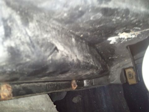 1994 Ford Bronco - Close-up view of the underside of a vehicle component, revealing rust and dirt.