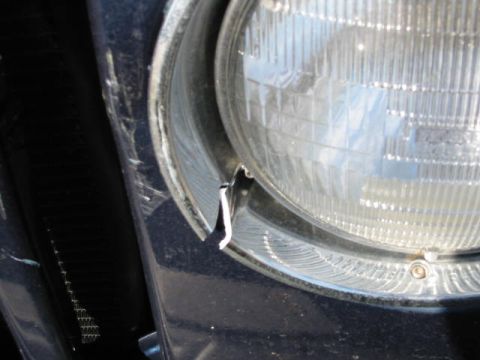 2002 Jeep Wrangler - Close-up of a damaged headlight bezel on a 2002 Jeep Wrangler, indicating wear or impact.
