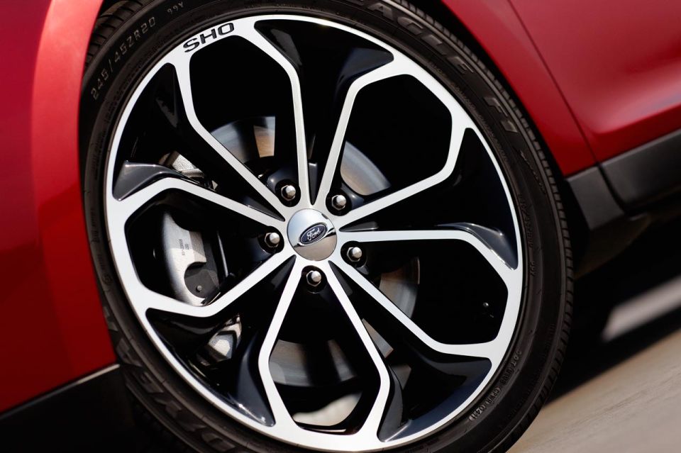 Close-up of a black and silver alloy wheel with 'SHO' text on a red car